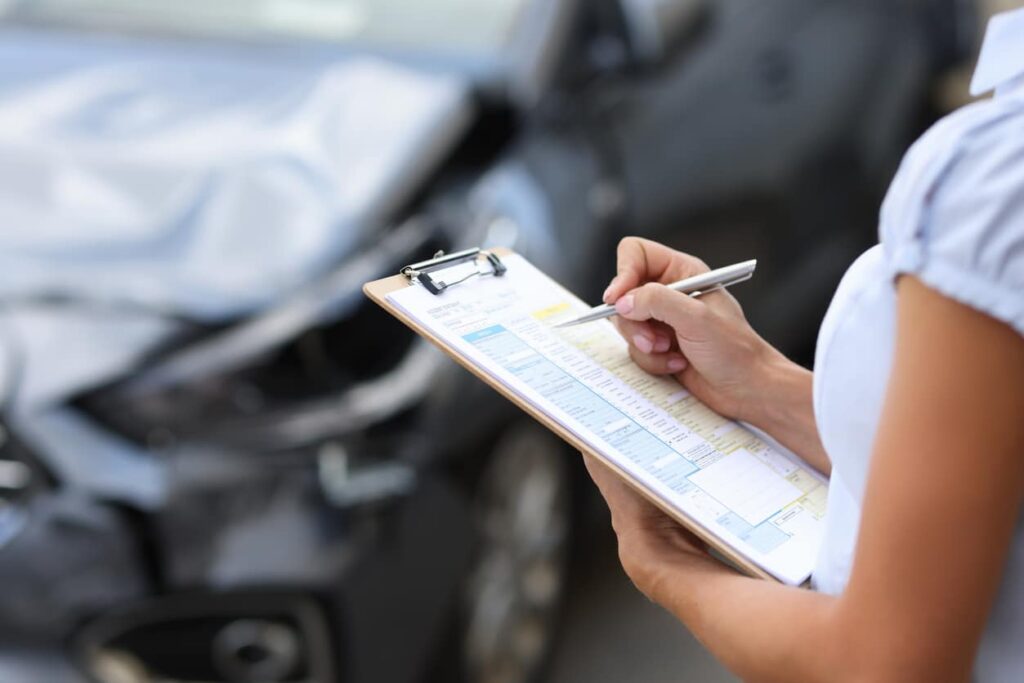 Car Accident Damages Insurance agent conducts inspection of the damaged car by filling out documents