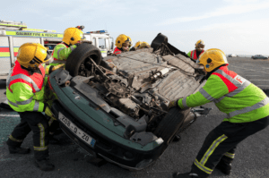 fire department team attempting to flip over car after it rolled over in an accident