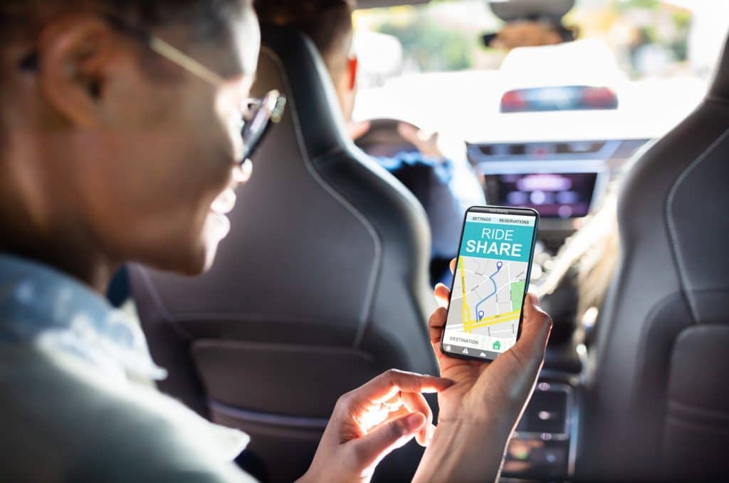 persona looking at rideshare app in vehicle